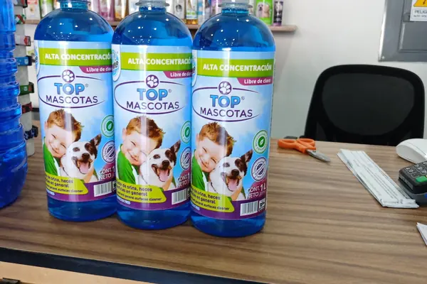 Tres botellas de Top Mascotas sobre un escritorio